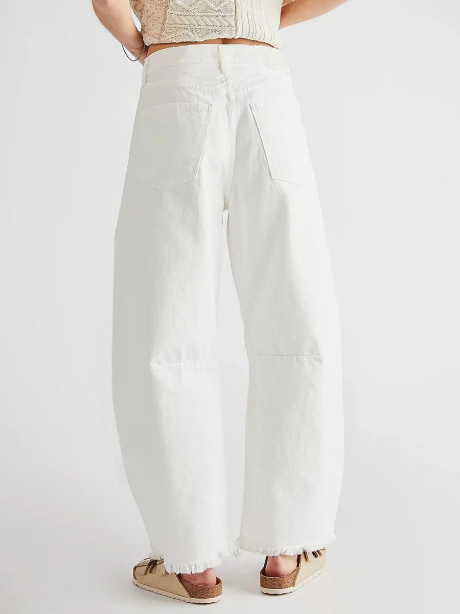 Back view of high-waisted white wide-leg jeans with frayed hems and tan slide sandals.
