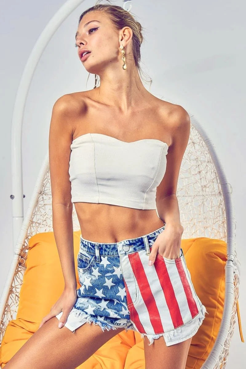 Distressed denim shorts with a stars and stripes pattern and frayed hem.