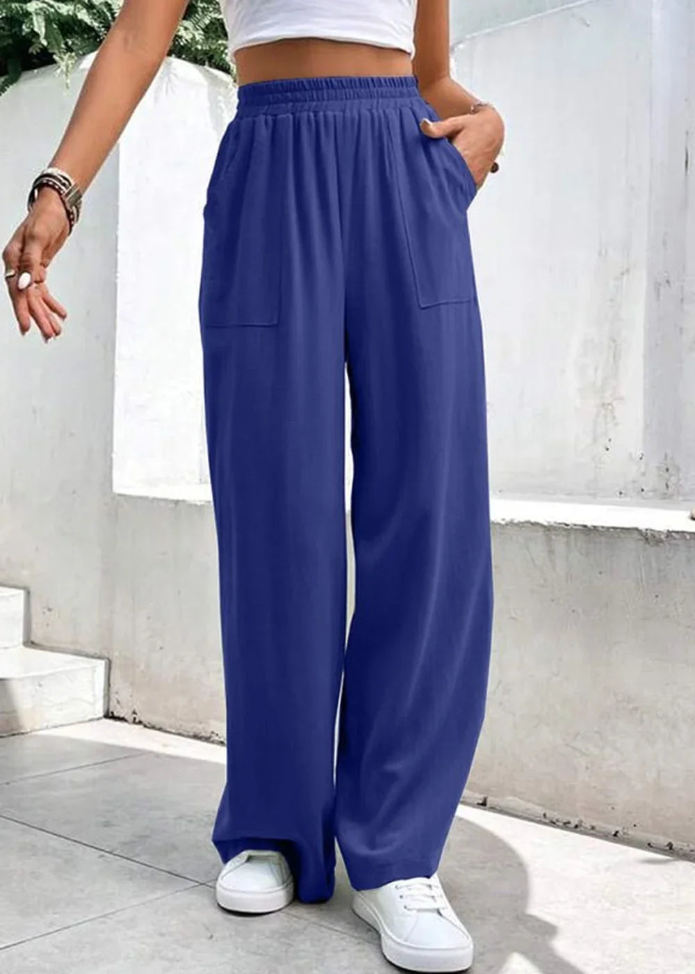Navy blue wide-leg pants with pockets and white sneakers on a model.