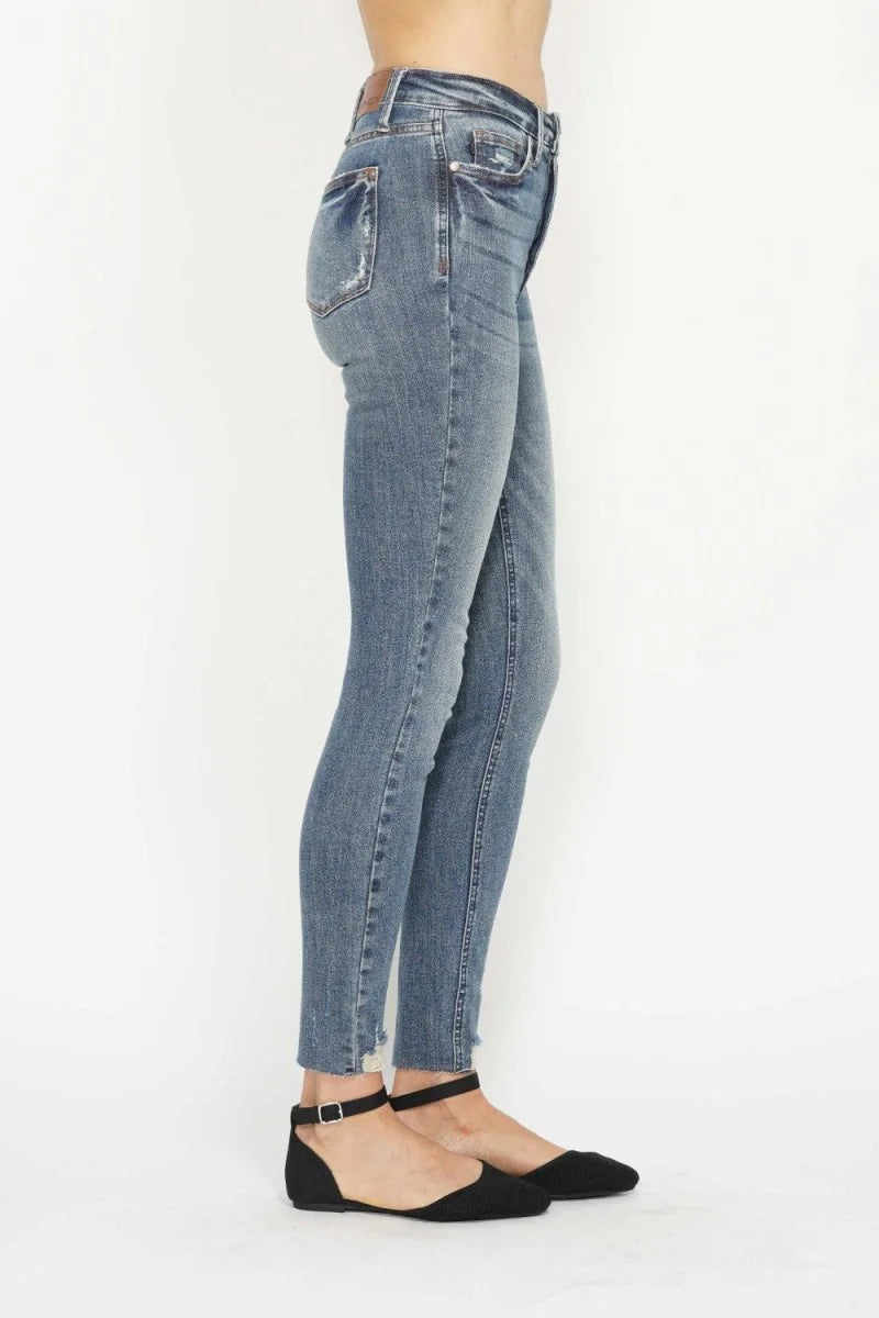 Light blue distressed denim jeans with frayed hem, shown on model with black ballet flats.