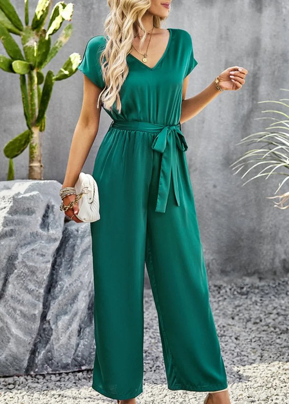 Emerald green wide-leg jumpsuit with V-neck, short sleeves, and a self-tie belt on a model.