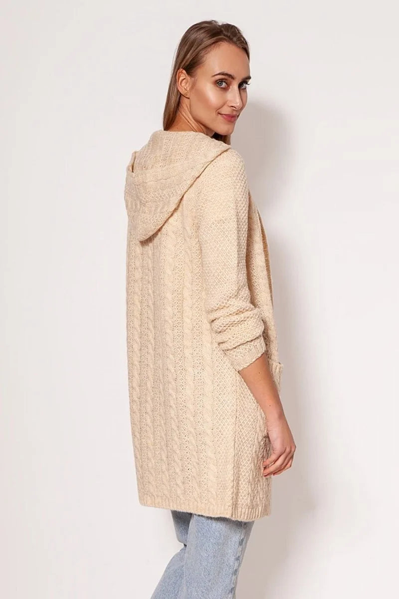 Woman wearing a cream cable knit hooded cardigan with pockets, styled with light wash jeans.