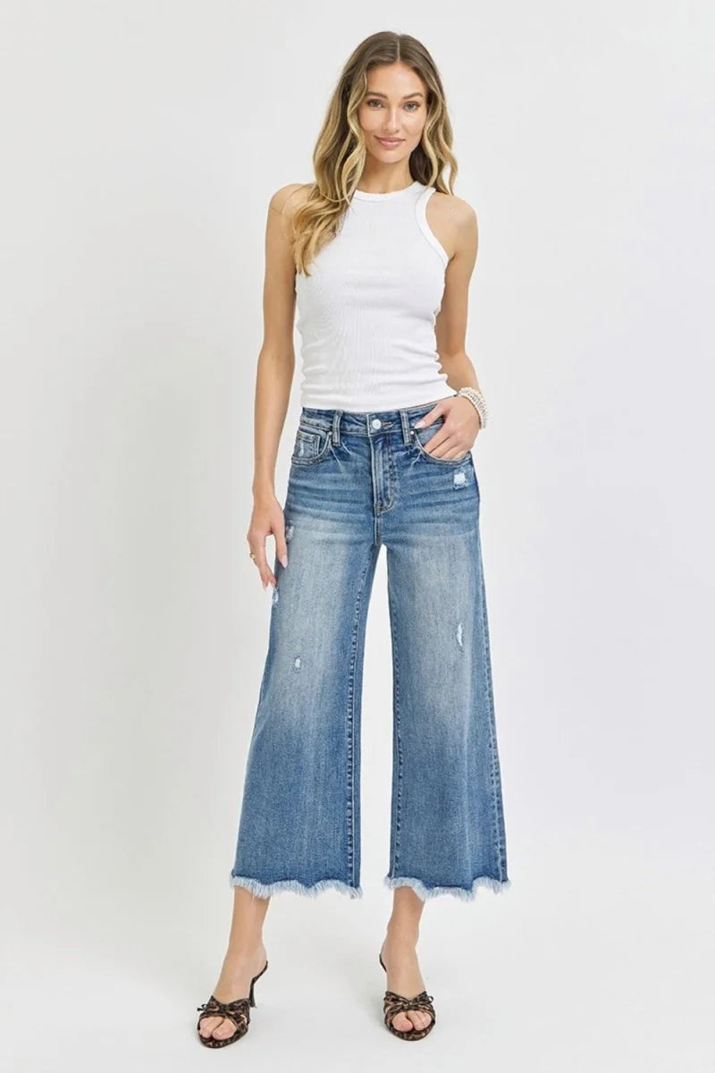 Distressed denim wide-leg cropped jeans with frayed hem, on model.