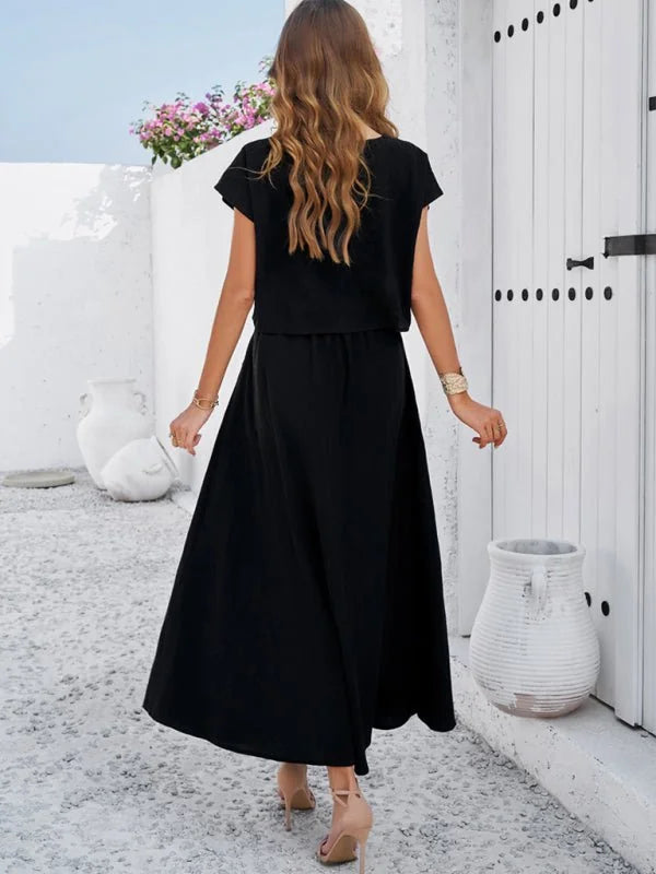 Black two-piece outfit with flowing skirt and cropped top, worn by a model from the back.