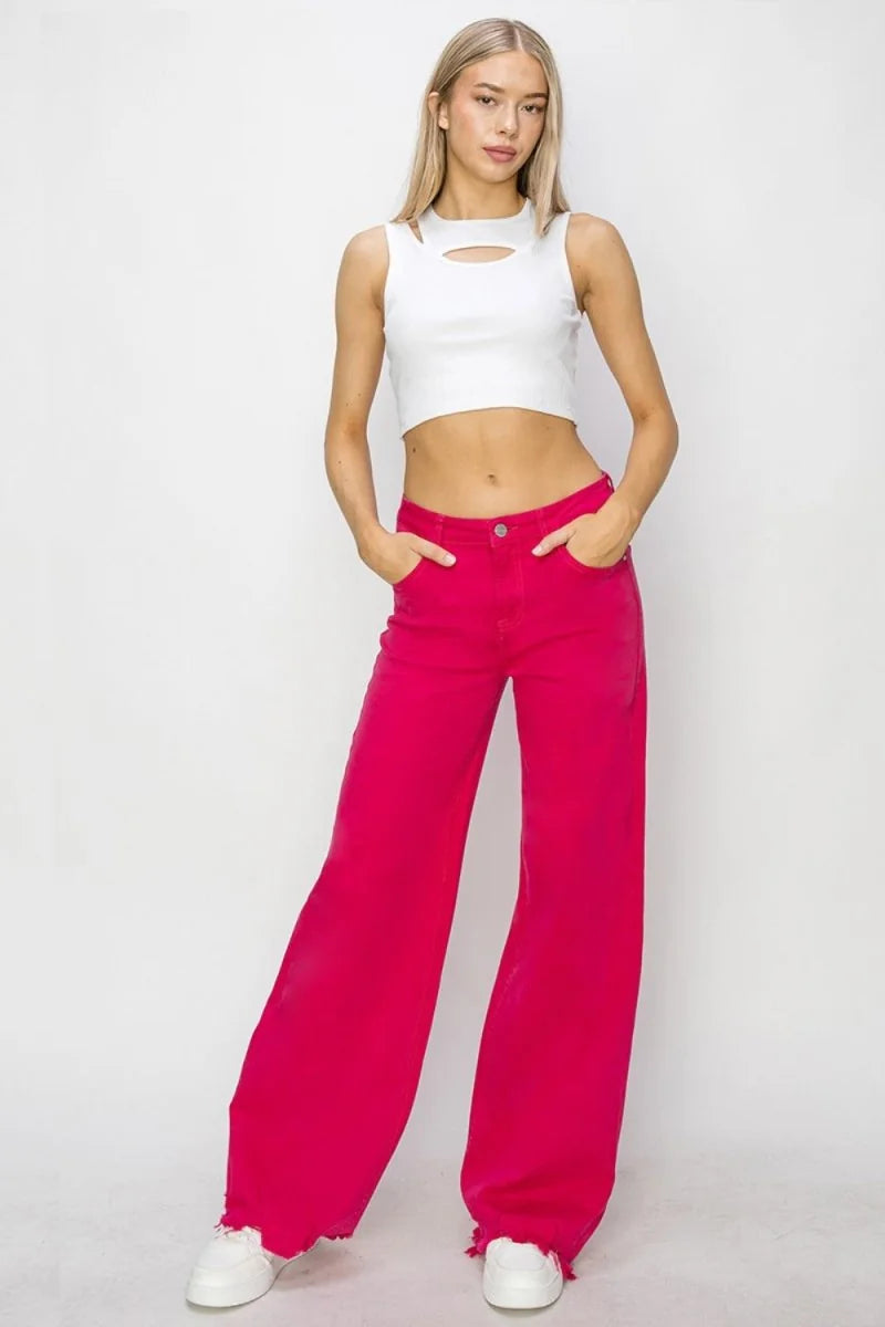 Wide-leg magenta jeans with frayed hem and white sneakers on model.