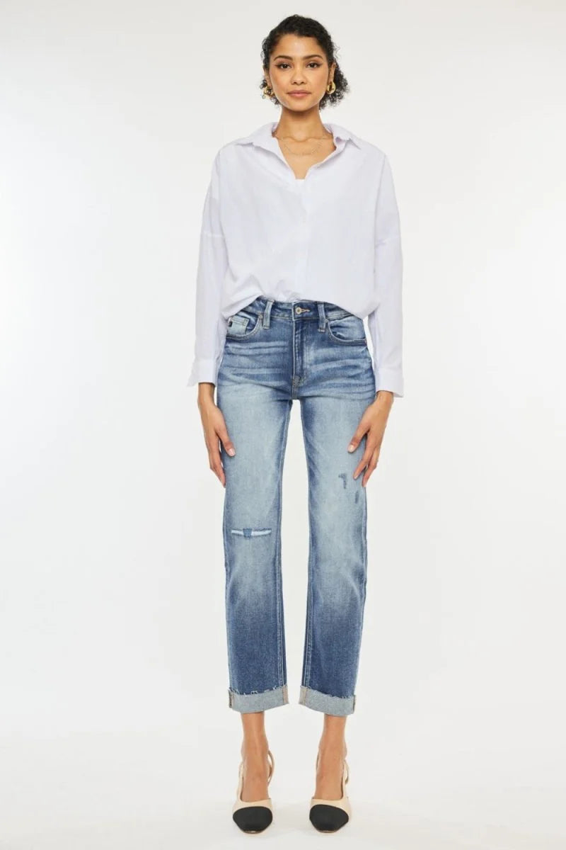 Light wash distressed denim jeans with a cuffed hem, worn by a model.