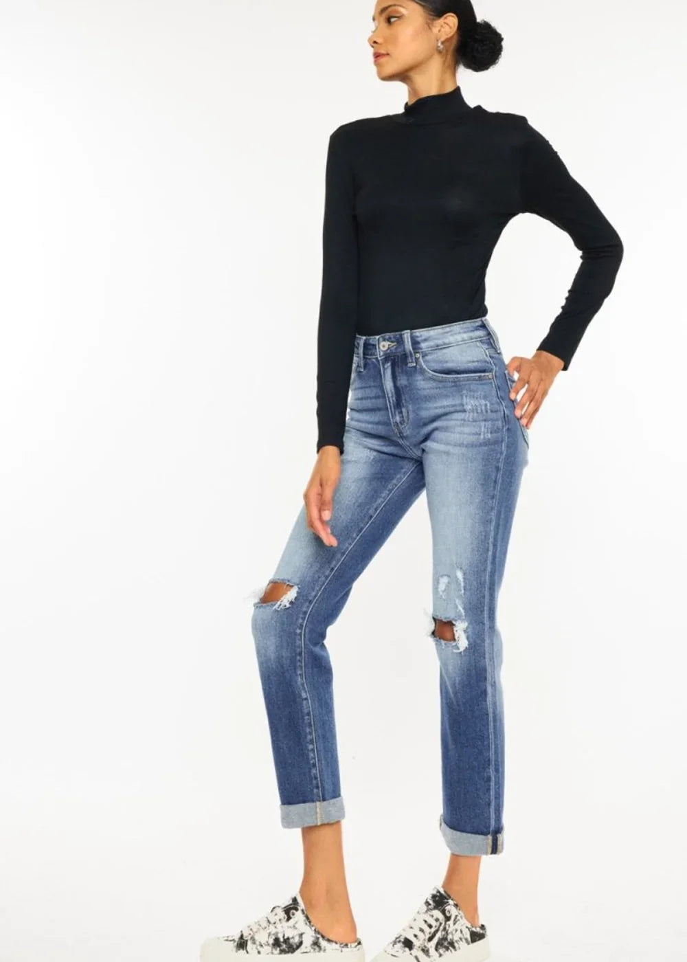 Distressed mid-wash denim jeans with ripped knees and cuffed hems, worn by a model.