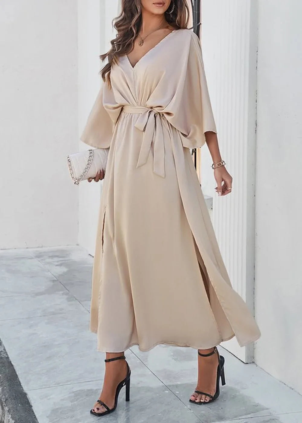 Beige V-neck maxi dress with dolman sleeves, a tie waist, and high slits, worn by a model.