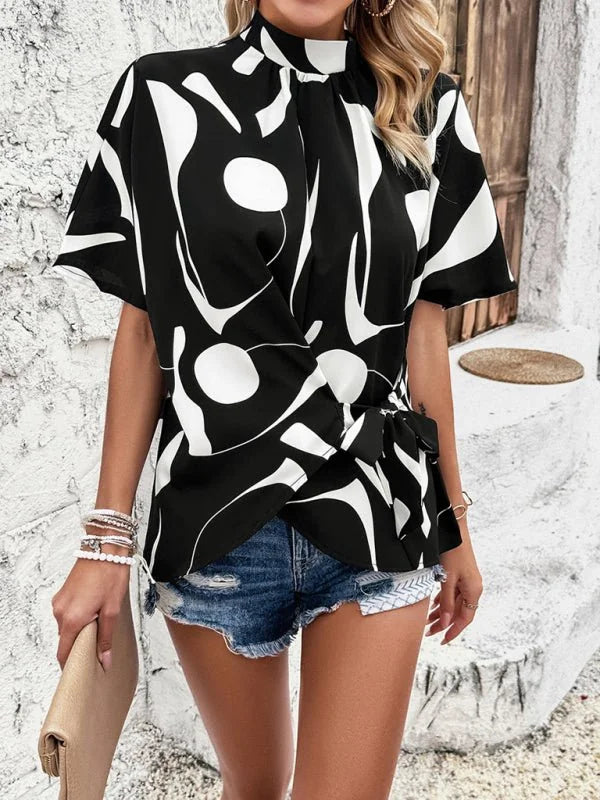Black and white abstract print wrap top with tie waist, paired with distressed denim shorts.