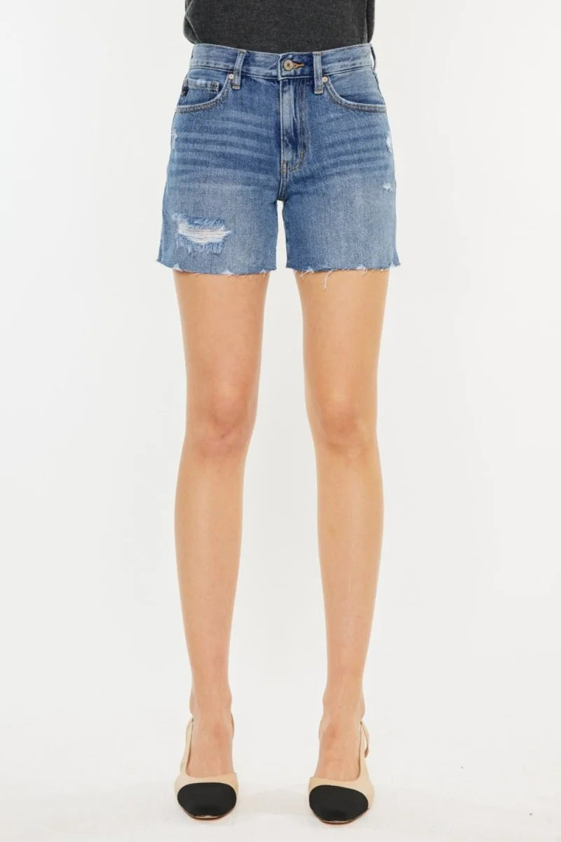 Distressed denim shorts with frayed hem, on model.