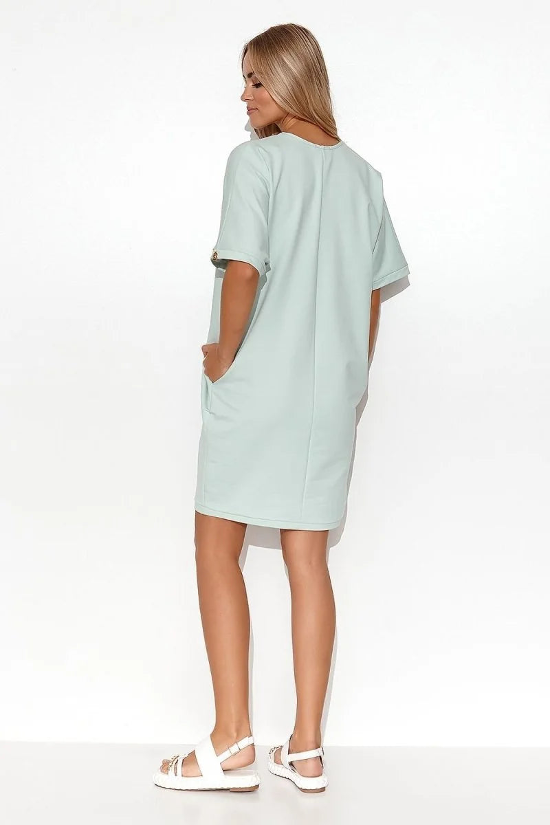 Light mint green cotton-spandex shift dress with short sleeves and pockets, shown from the back on a model.