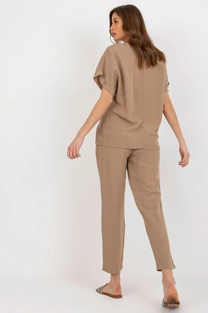 Woman from behind wearing a beige linen blend relaxed fit pant and matching top, with patterned sandals.