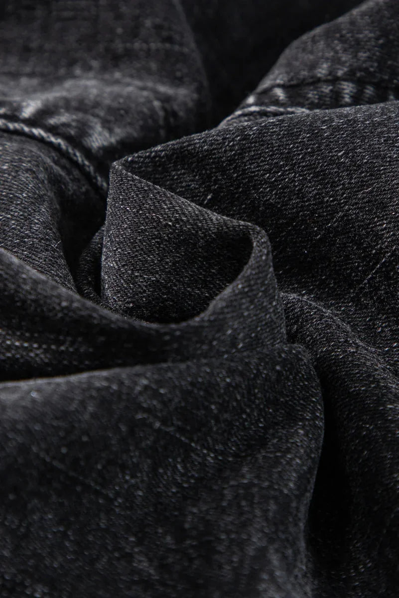 Close-up of dark grey denim fabric with textured weave and subtle whiskering.