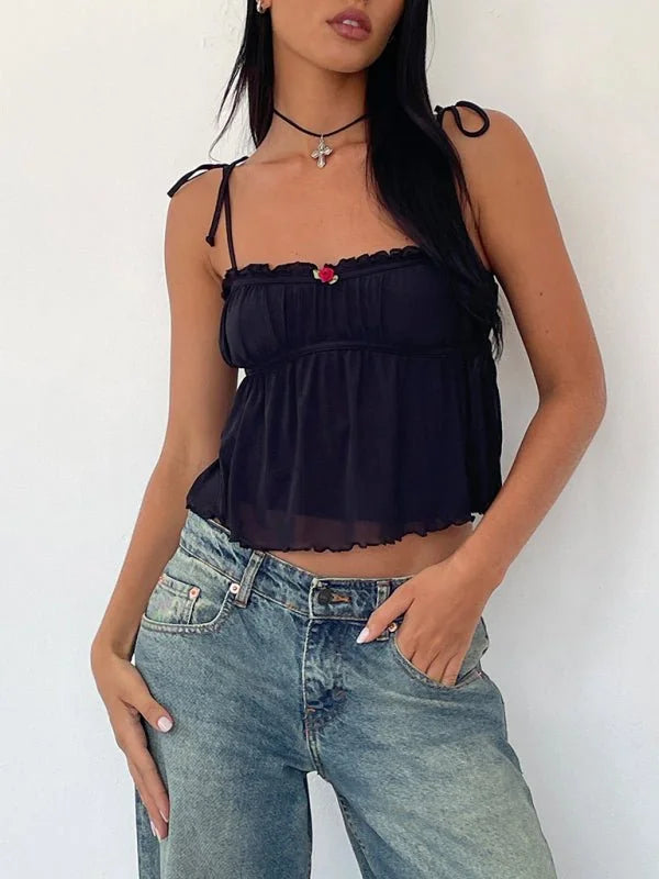 Black chiffon cami with tie straps and a rose detail, paired with light wash distressed jeans.