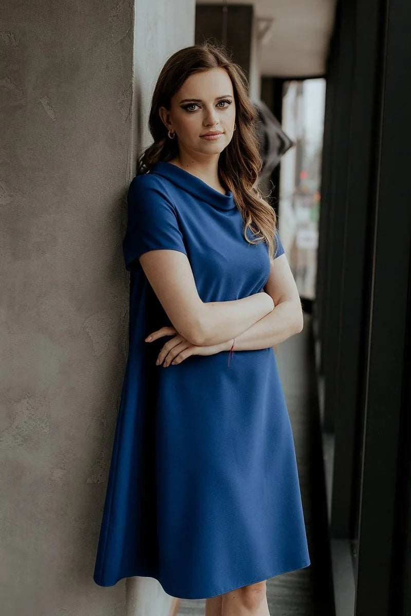 Loose fit, navy blue day dress with short sleeves and cowl neckline on a model.