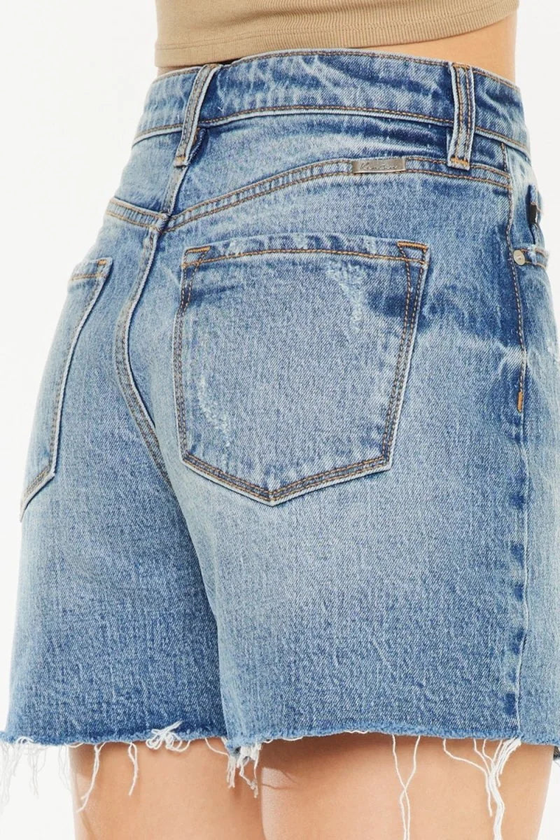 Close-up of light blue distressed denim shorts with a frayed hem.