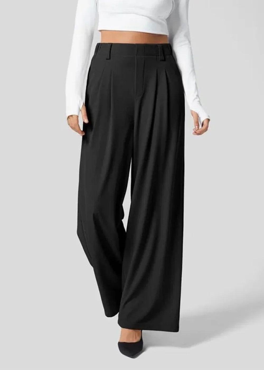 Black wide-leg pleated trousers with a high waist, on a model wearing a white long-sleeved top.