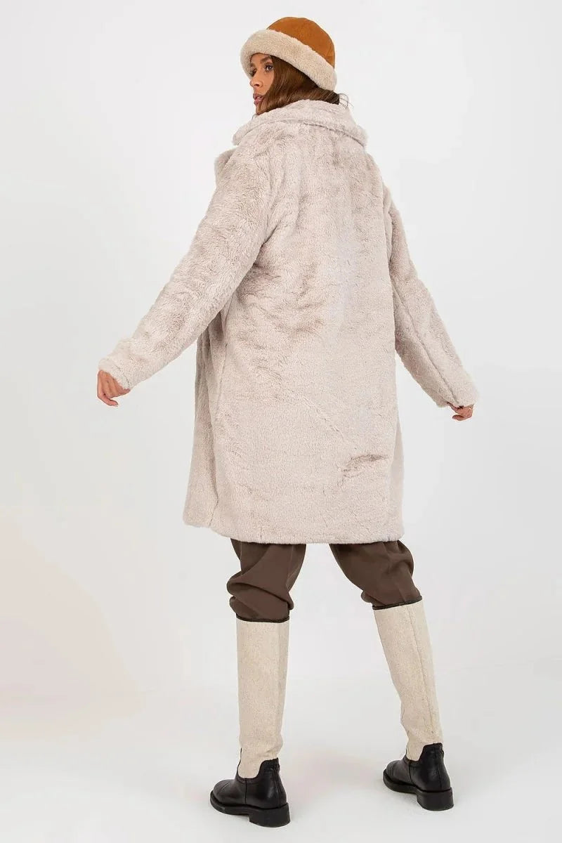 Cream fuzzy coat with brown pants and tall cream boots on model