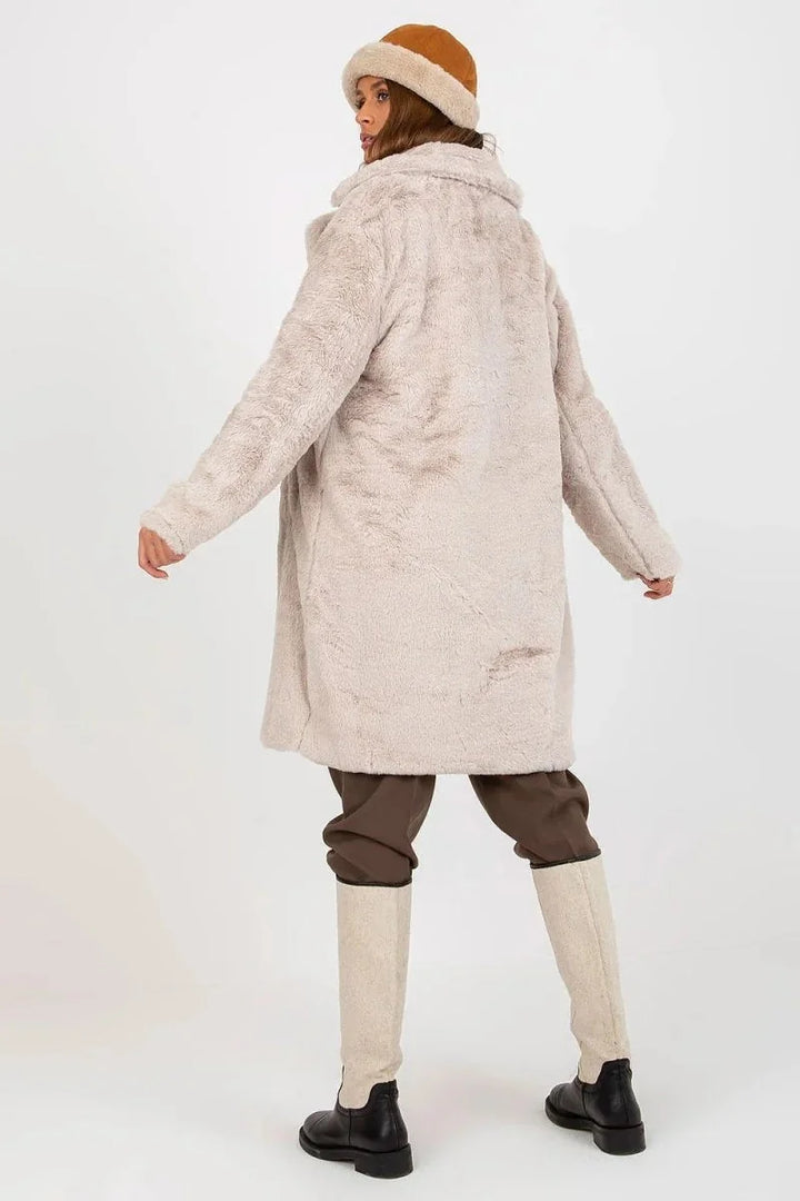 Cream fuzzy coat with brown pants and tall cream boots on model