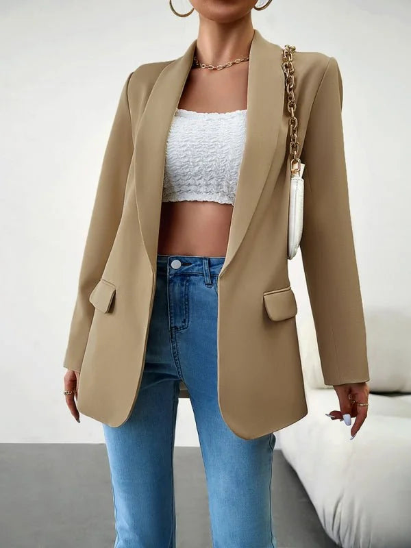 Tan blazer with a smooth texture, worn over a white smocked tube top and light wash jeans.