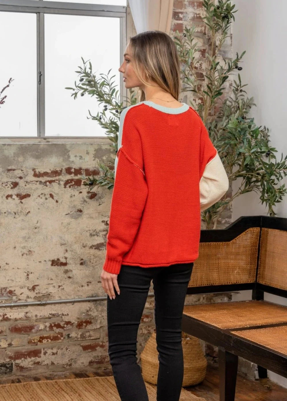 Red and cream relaxed fit sweater with light blue trim, worn by a model.
