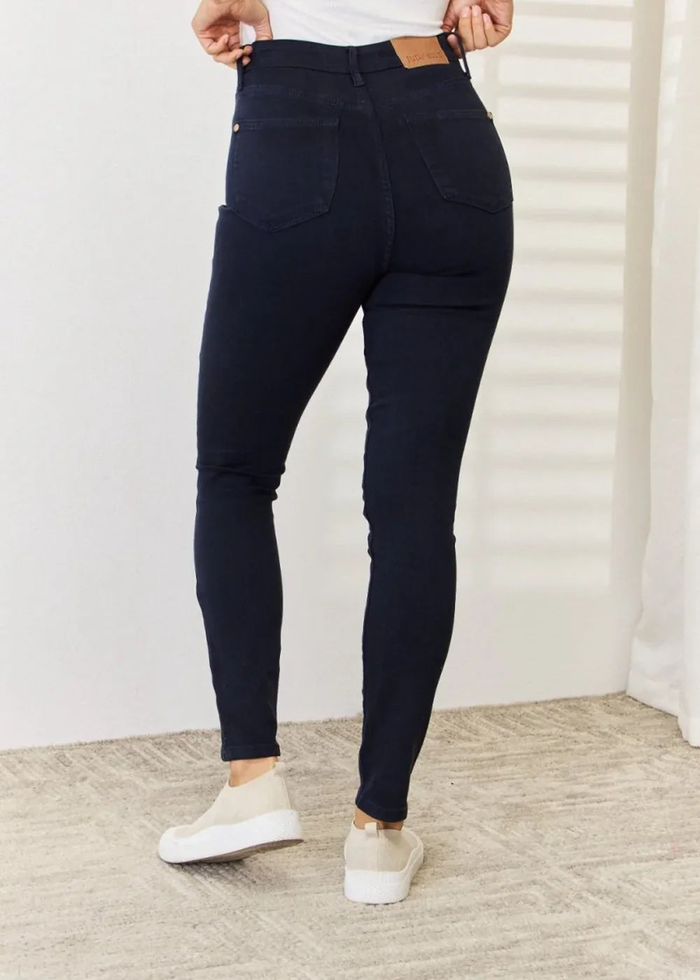 Navy blue skinny jeans with a fitted waist and casual sneakers on model.