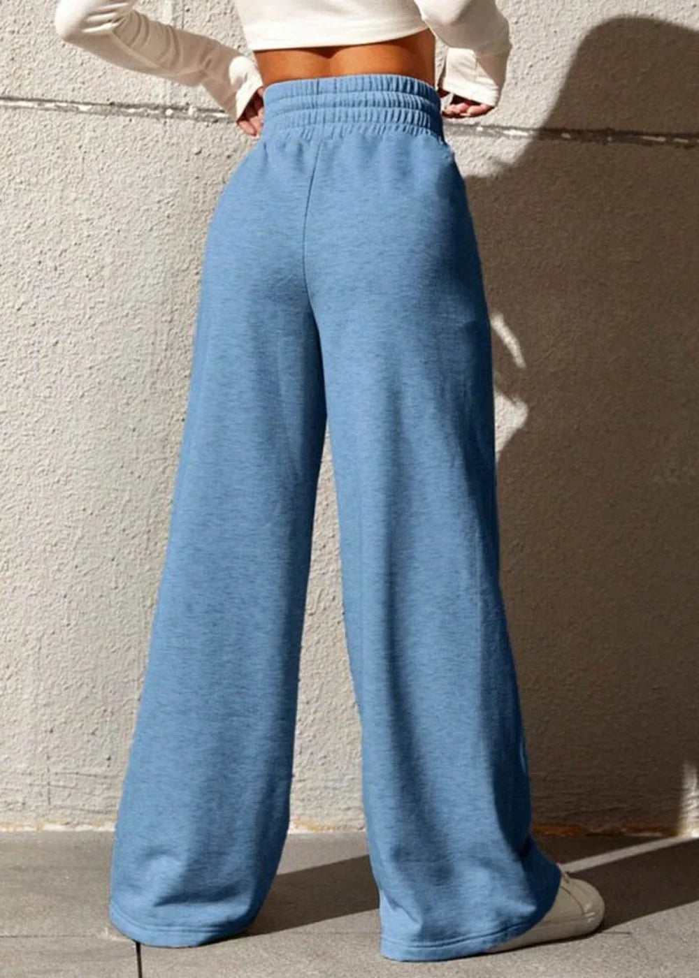 Light blue wide-leg sweatpants with a cinched waistband, shown on a model from the back.