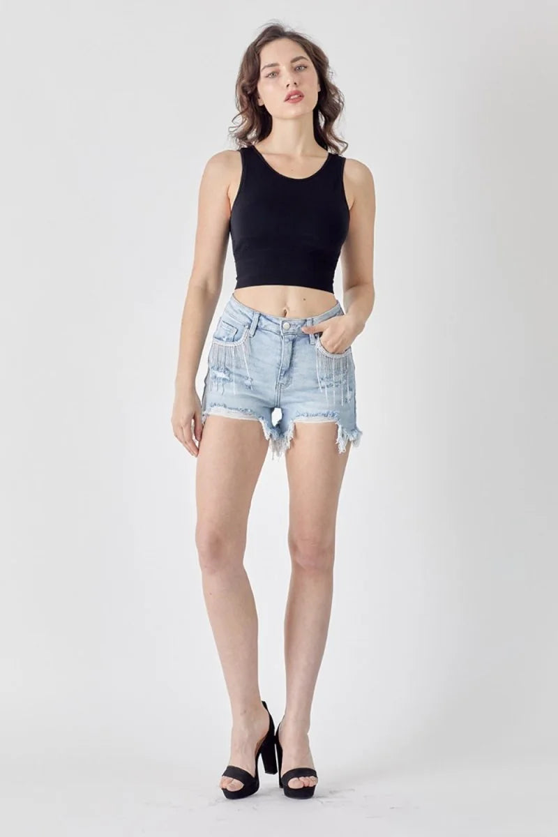 Light wash distressed denim shorts with fringe detail and frayed hem on model.