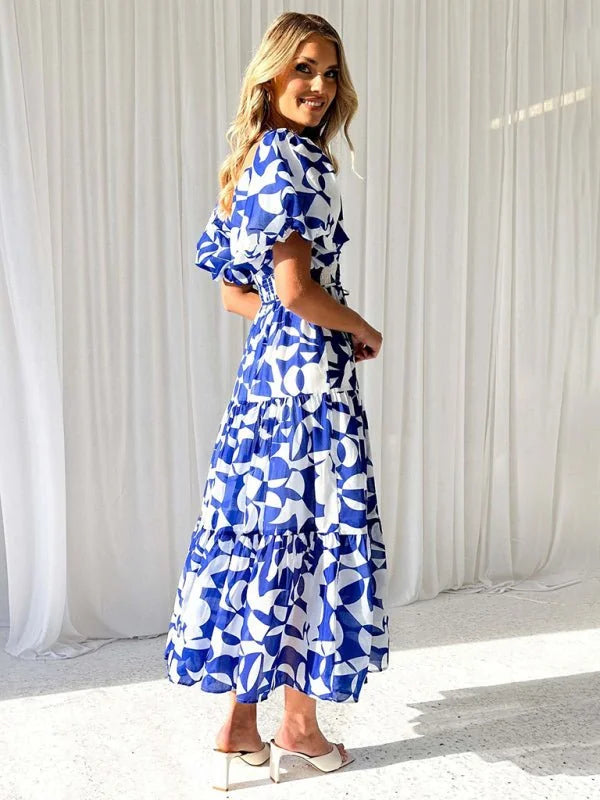 Blue and white abstract print midi dress with tiered skirt and puff sleeves on model.
