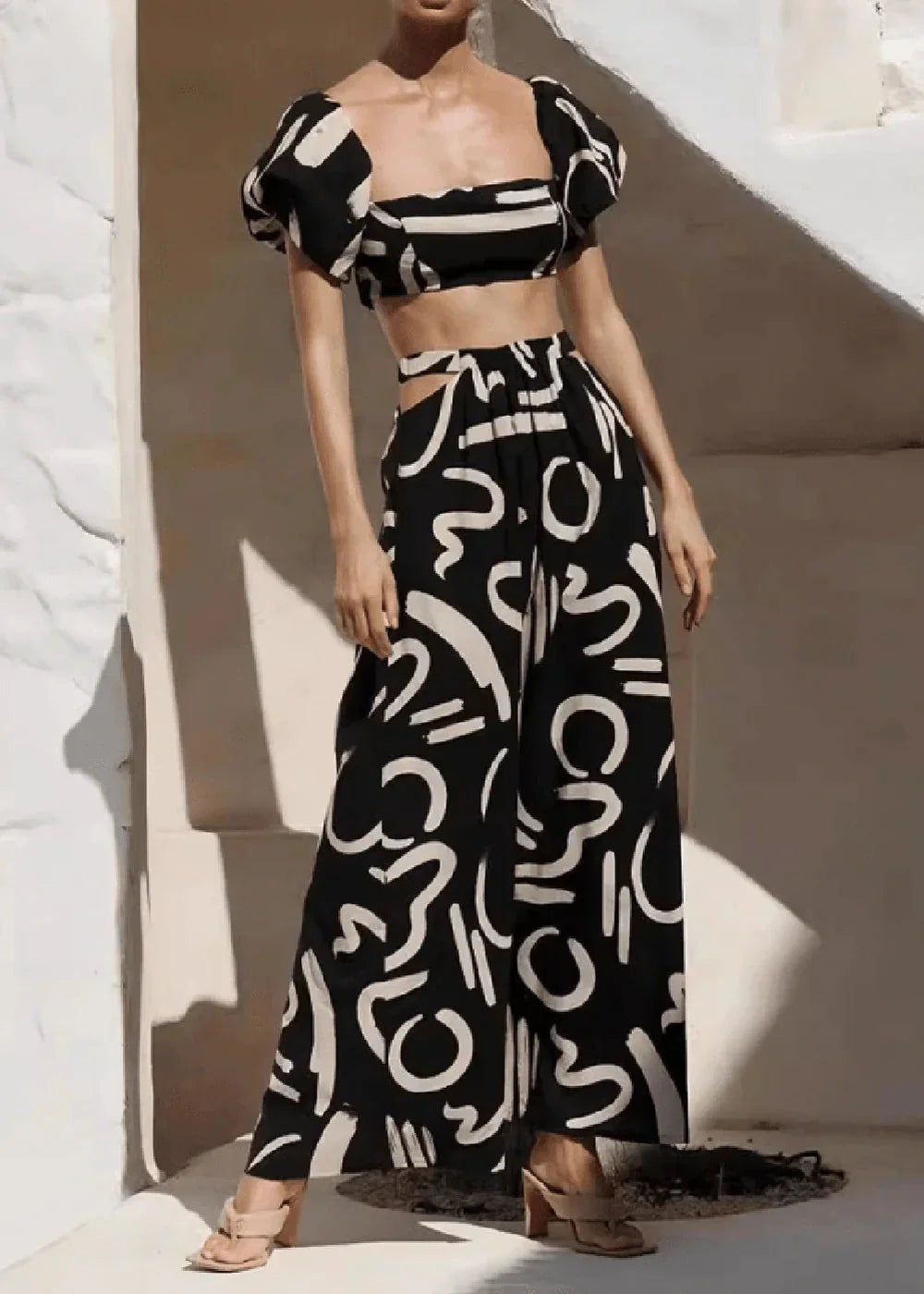 Black and white abstract print crop top with puff sleeves and matching wide-leg pants with cutouts.