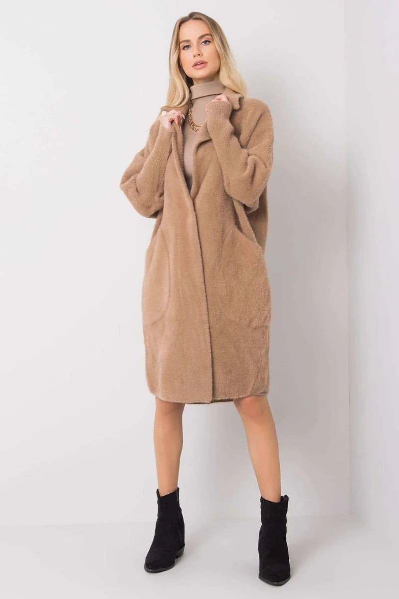 Woman in fuzzy brown cardigan with pockets and black ankle boots, full body shot.