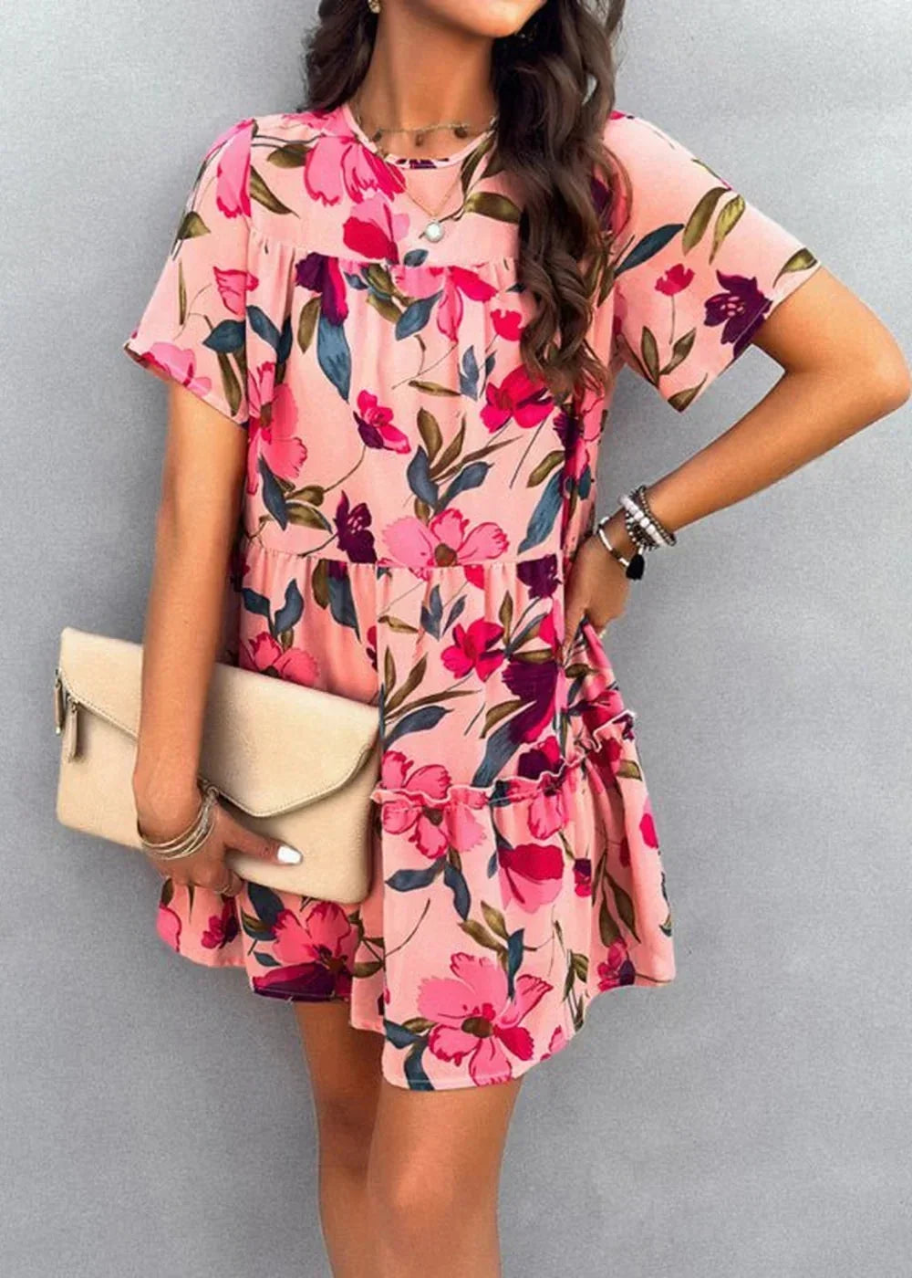 Pink floral print tiered mini dress with short sleeves and a clutch purse.