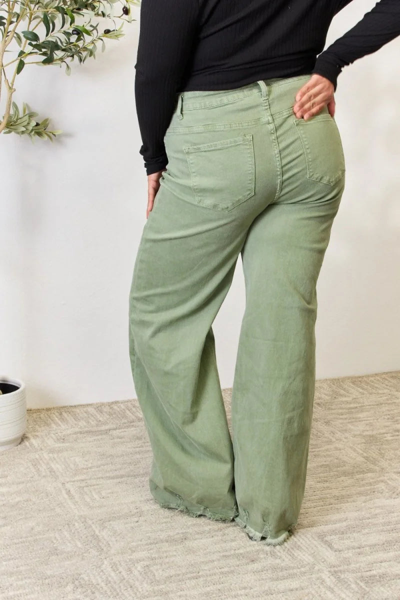 Sage green high-waisted wide-leg pants with frayed hem, seen from the back on a model.