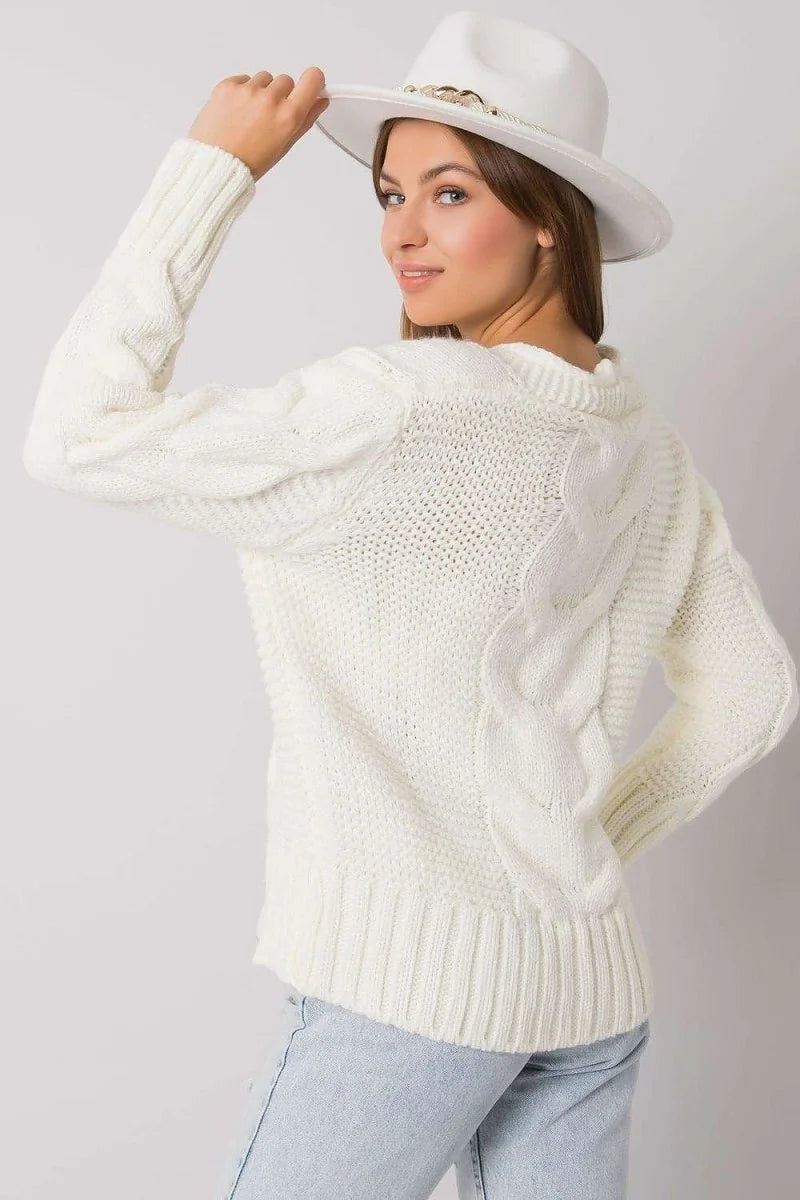 Cream cable knit sweater with a textured weave and ribbed trim, worn by a model with a white hat.