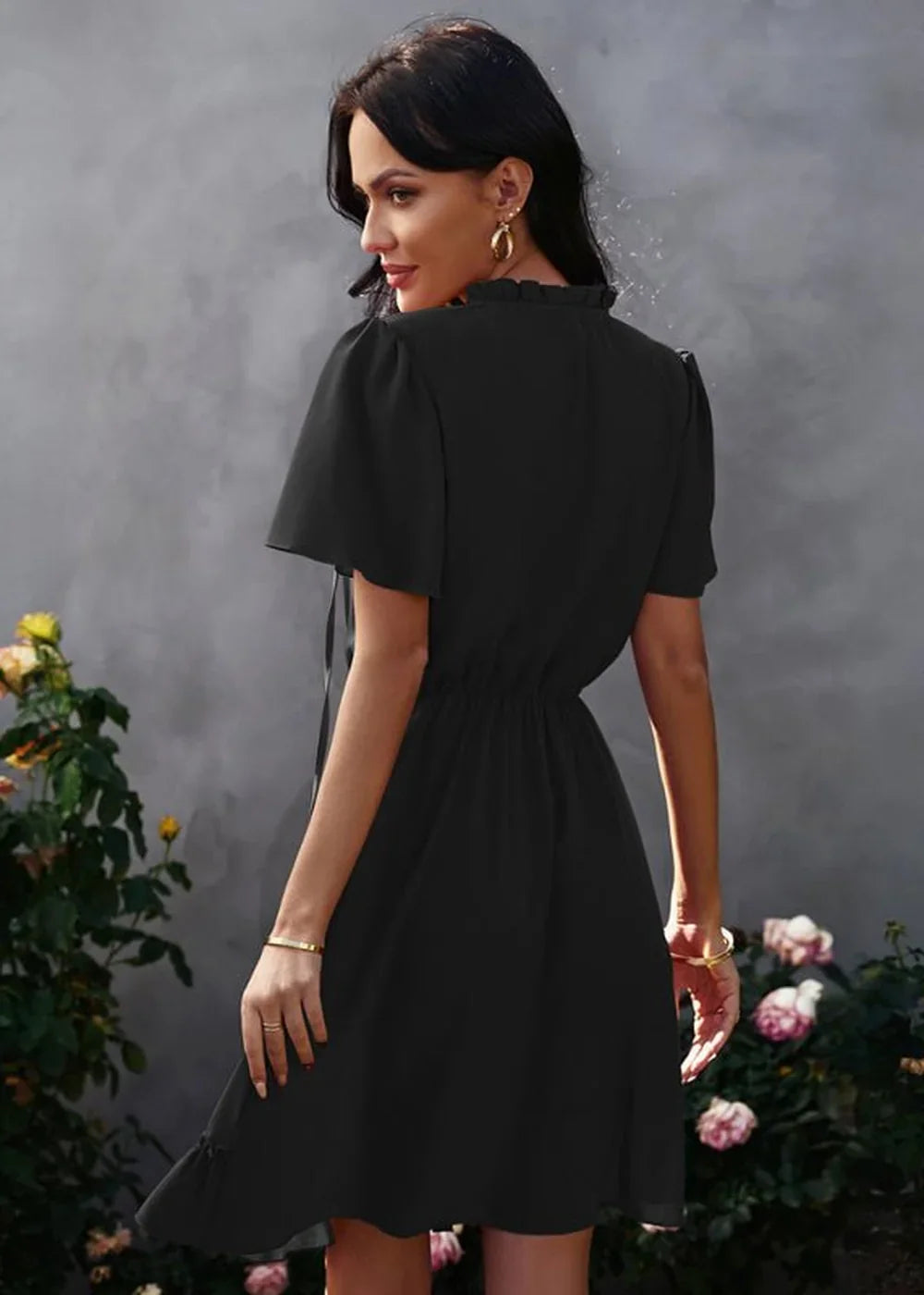 Black short-sleeve dress with ruffled neckline and cinched waist, worn on model.