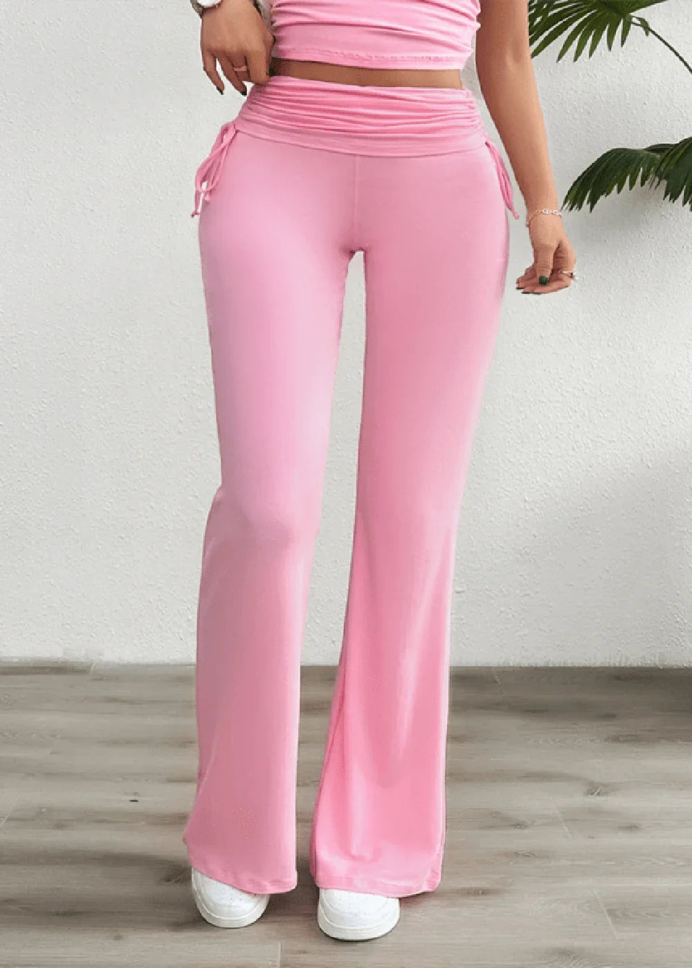 Pink flared pants with ruched drawstring waistband and white sneakers