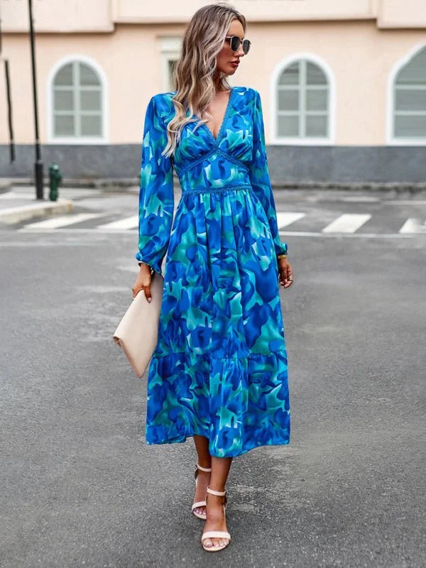 Blue and green abstract print midi dress with V-neck and long sleeves, worn by a model.
