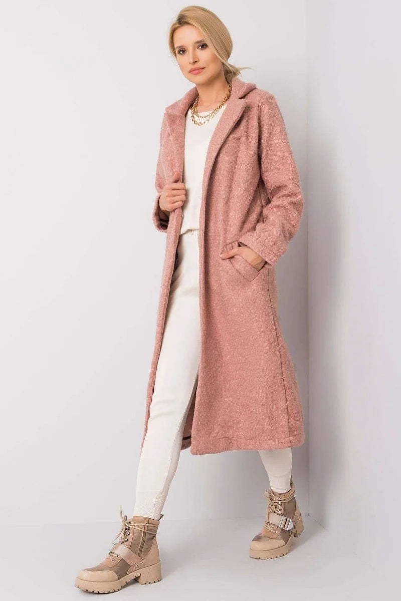 Pink textured long coat with cream knit set and tan boots on model.