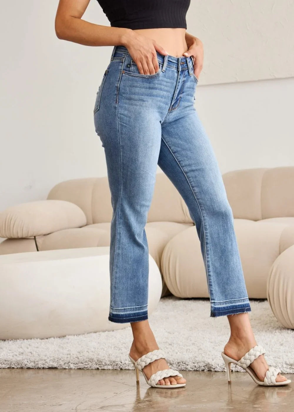 Medium wash denim jeans with frayed hem and a regular fit on a model.