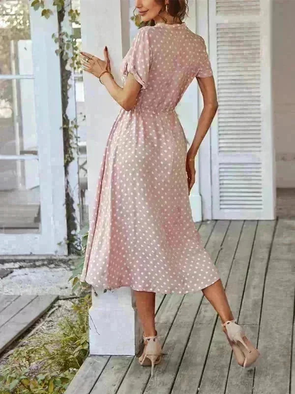 Pink polka dot rayon midi dress with short sleeves, cinched waist, and heeled sandals.