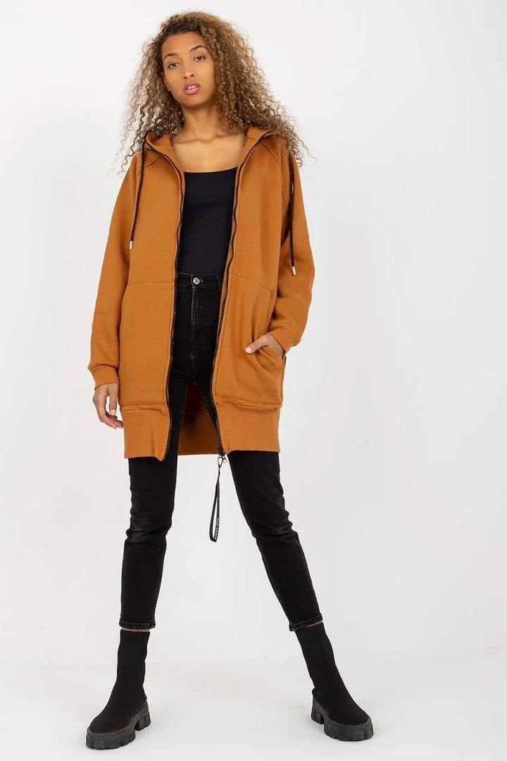 Woman in a relaxed fit, long brown zip-up hoodie with black accents and black skinny jeans.