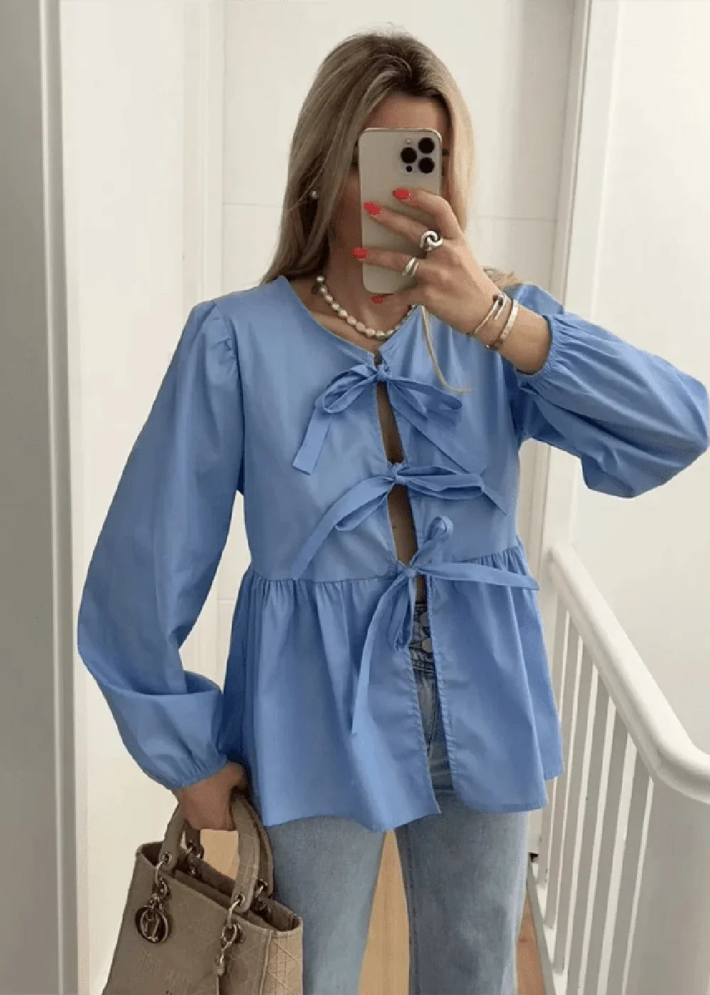 Light blue peasant blouse with tie-front detail and puff sleeves, worn by a model.