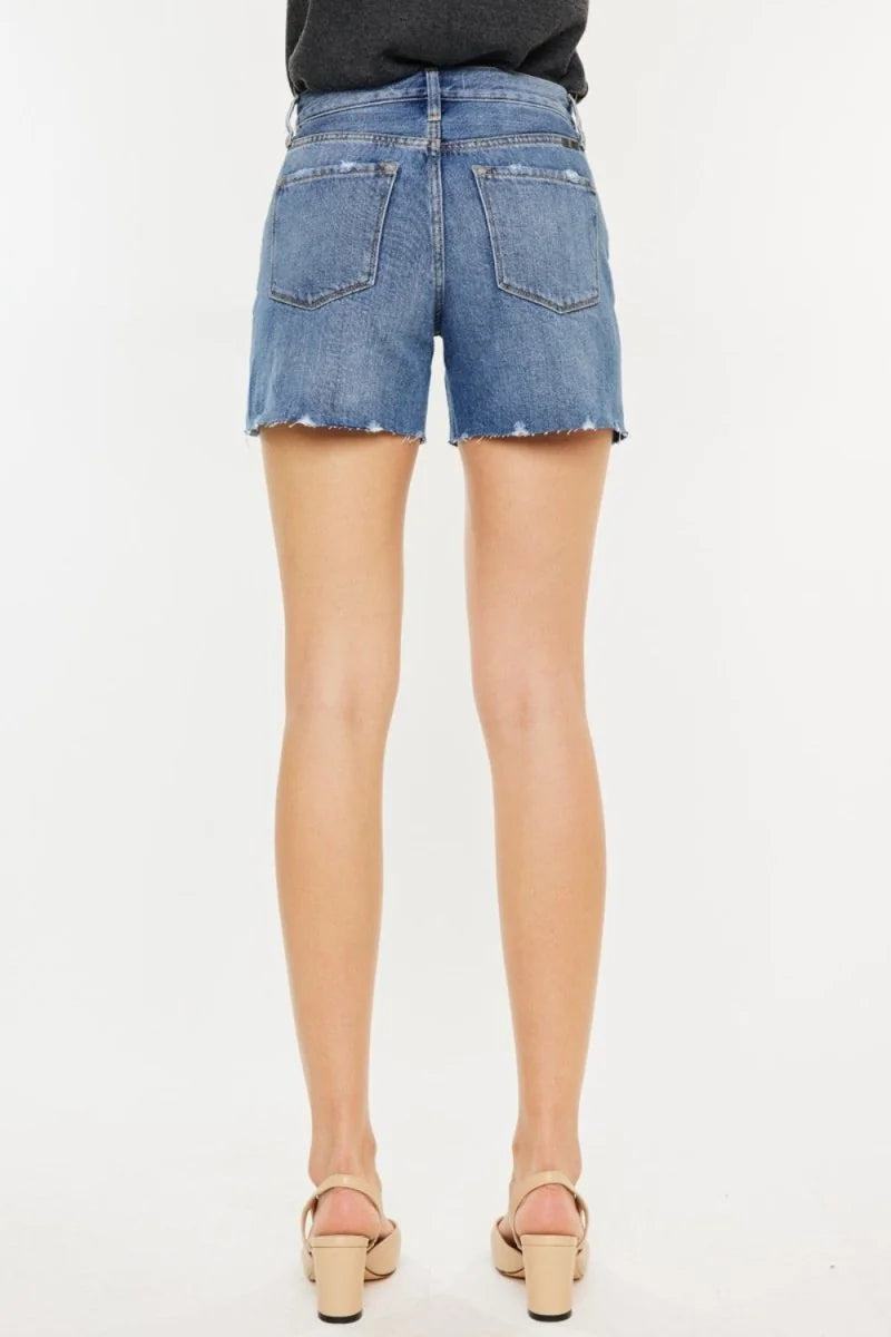 Back view of light wash distressed denim shorts with frayed hem.