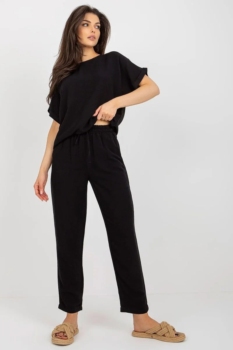 Black cotton-blend pants with a drawstring waist, on a model wearing woven slide sandals.