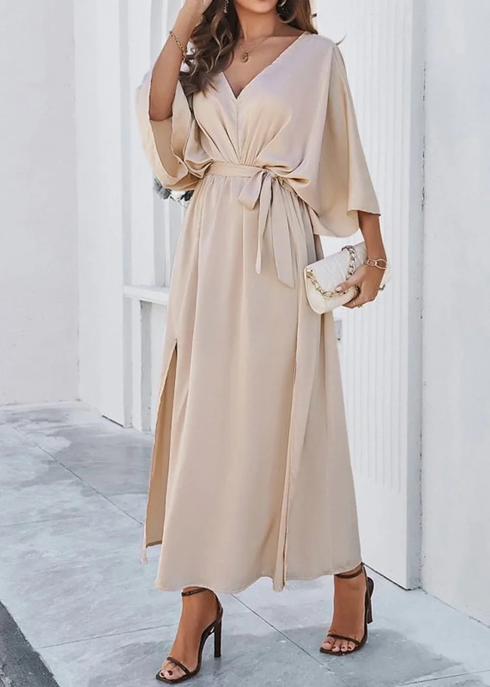 Elegant champagne satin maxi dress with V-neck, wide sleeves, and high slits, cinched with a self-tie belt.