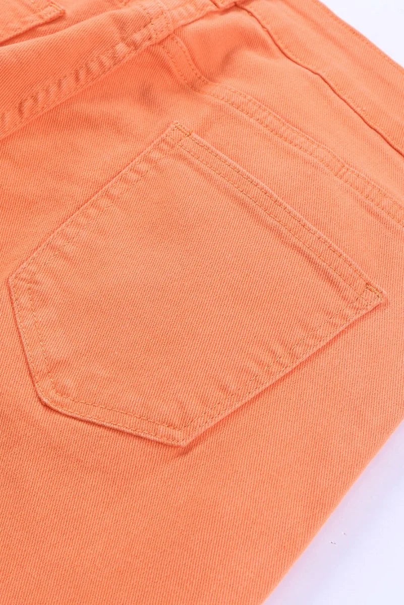Close-up of orange denim jeans showing a back pocket with double stitching and a textured fabric.