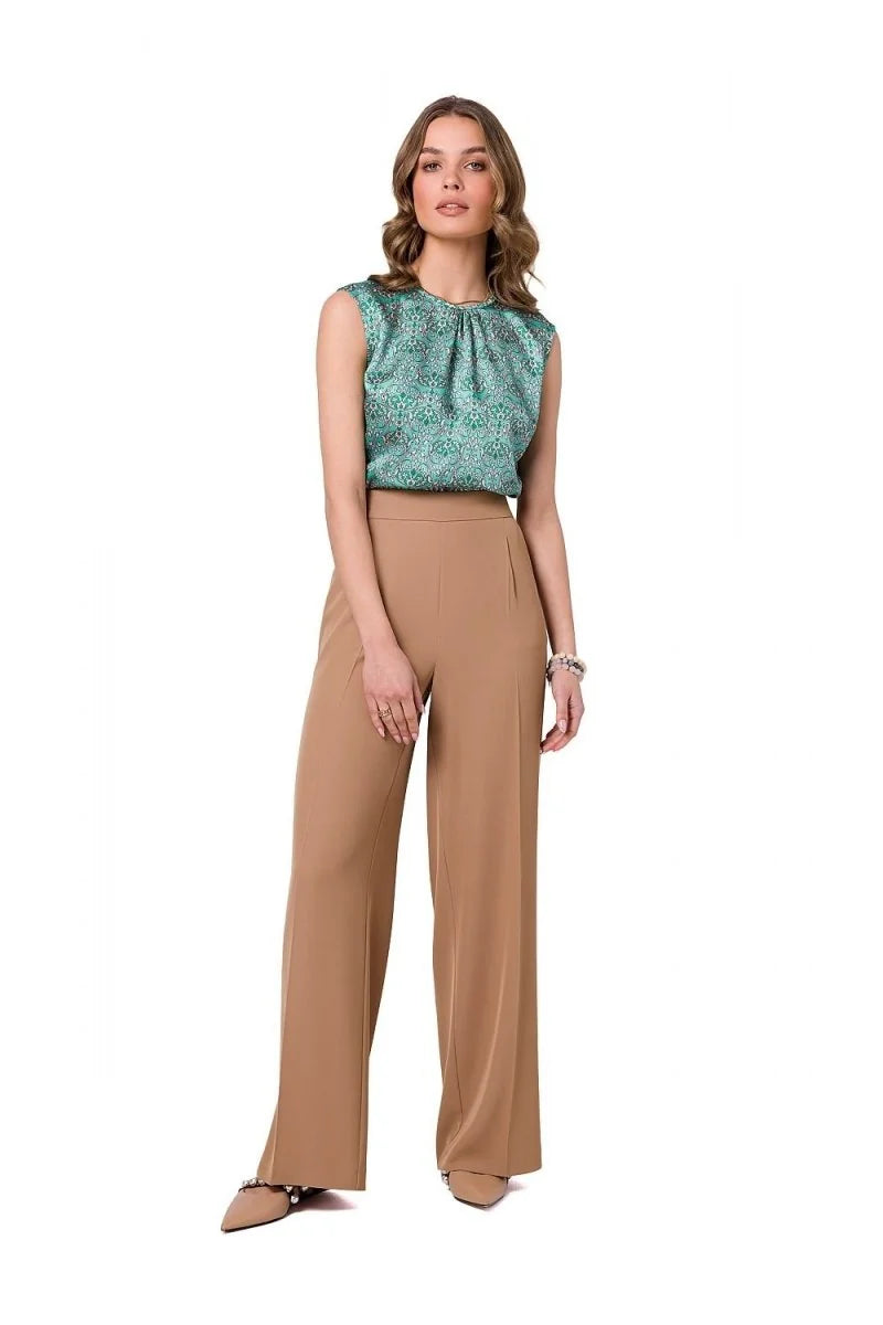 Woman in flowing camel-colored wide-leg pants with a subtle pleat detail and pointed-toe embellished flats.