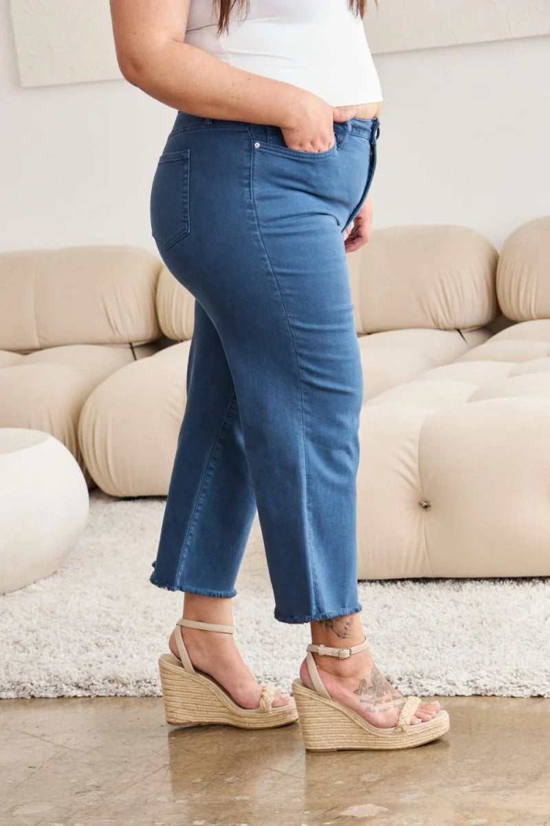Blue denim jeans with frayed hem and ankle strap wedge sandals on model.