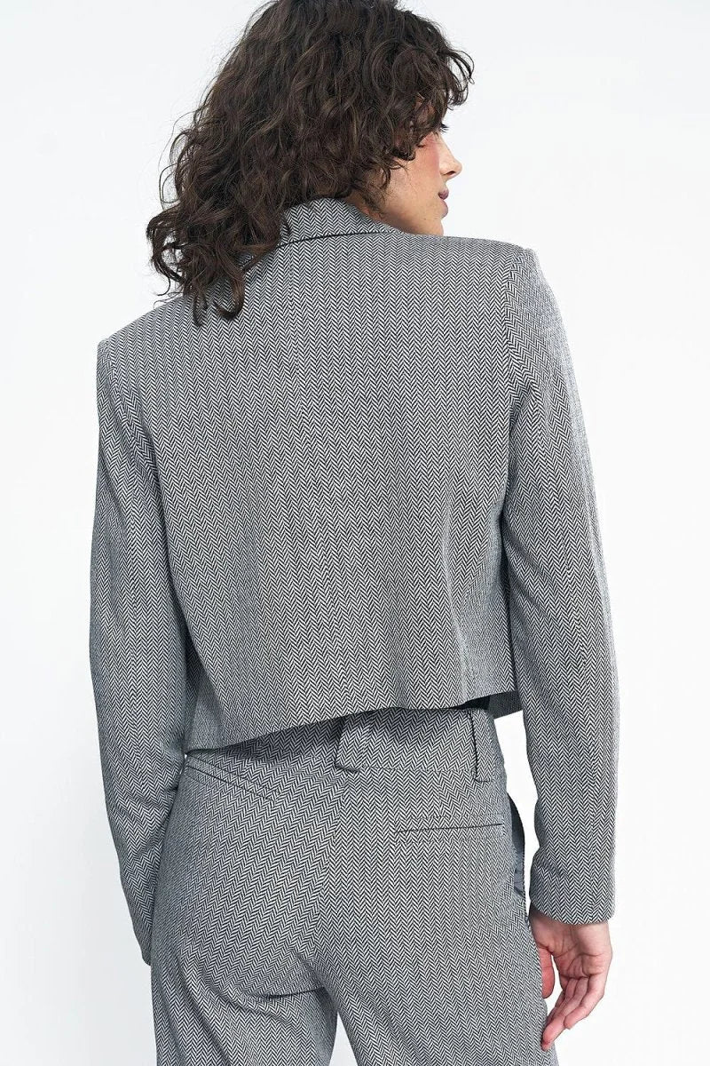 Back view of a cropped grey and white herringbone blazer on a model.