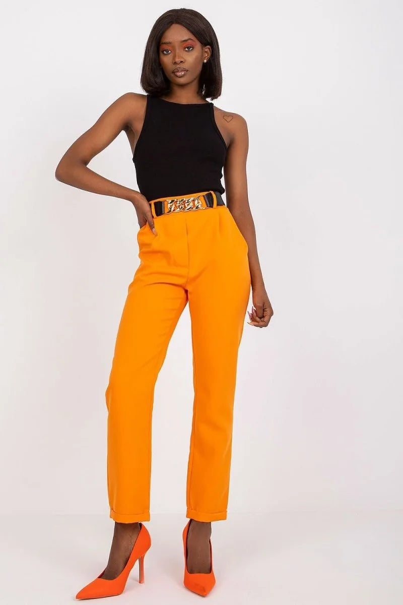 Orange high-waisted pants with a gold chain belt and black tank top on a model.